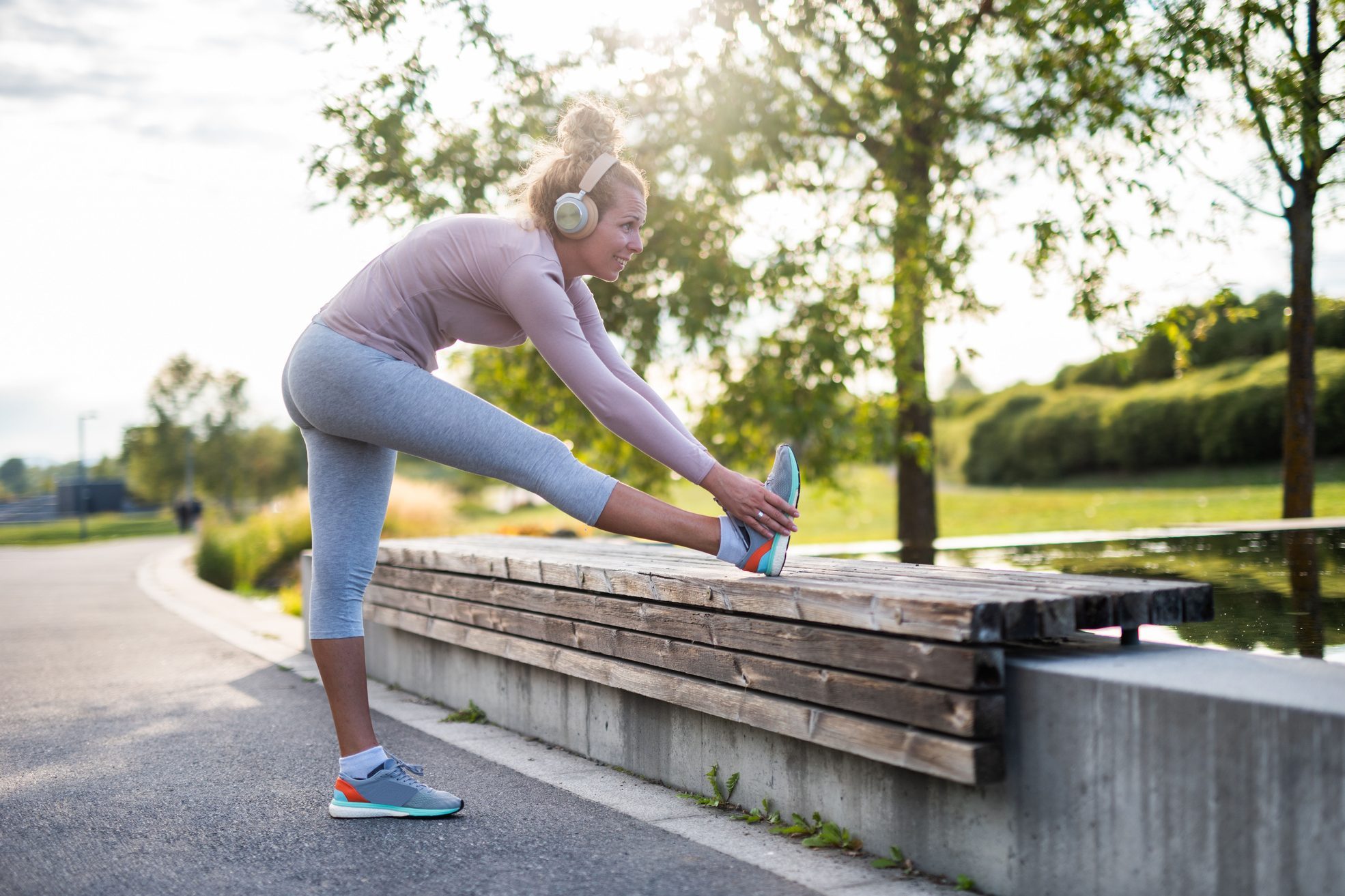 woman stretching her legs on bench in the park on a sunny day after walking exercise