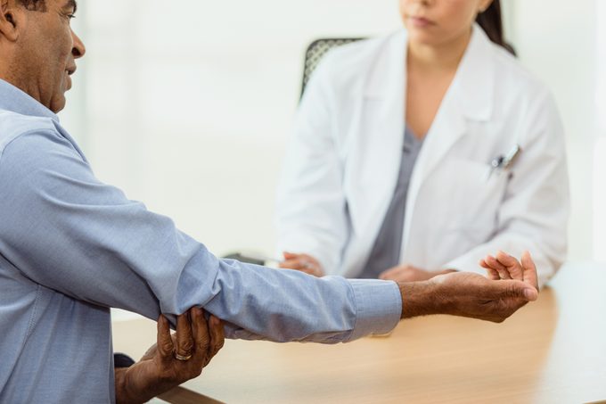 Male Patient Holds Out Arm To Show Doctor Elbow Pain