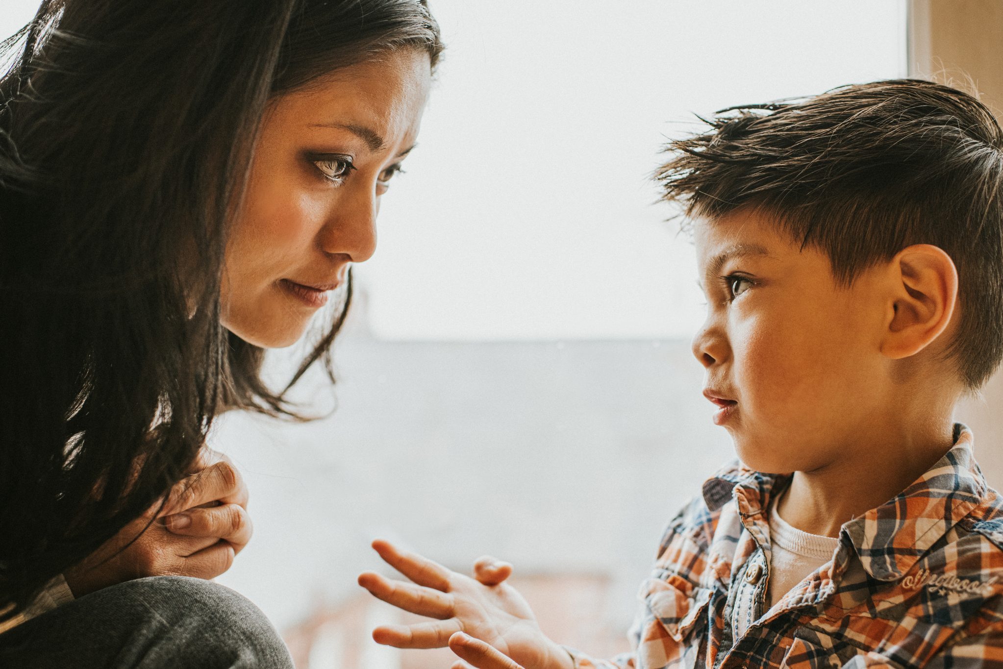 worried young boy talking to his mom