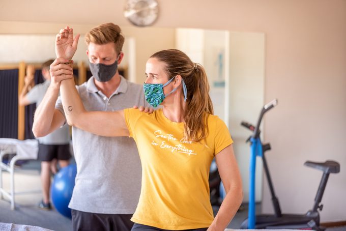 Physical Therapist Examining Arm and elbow Of A Woman At Rehab