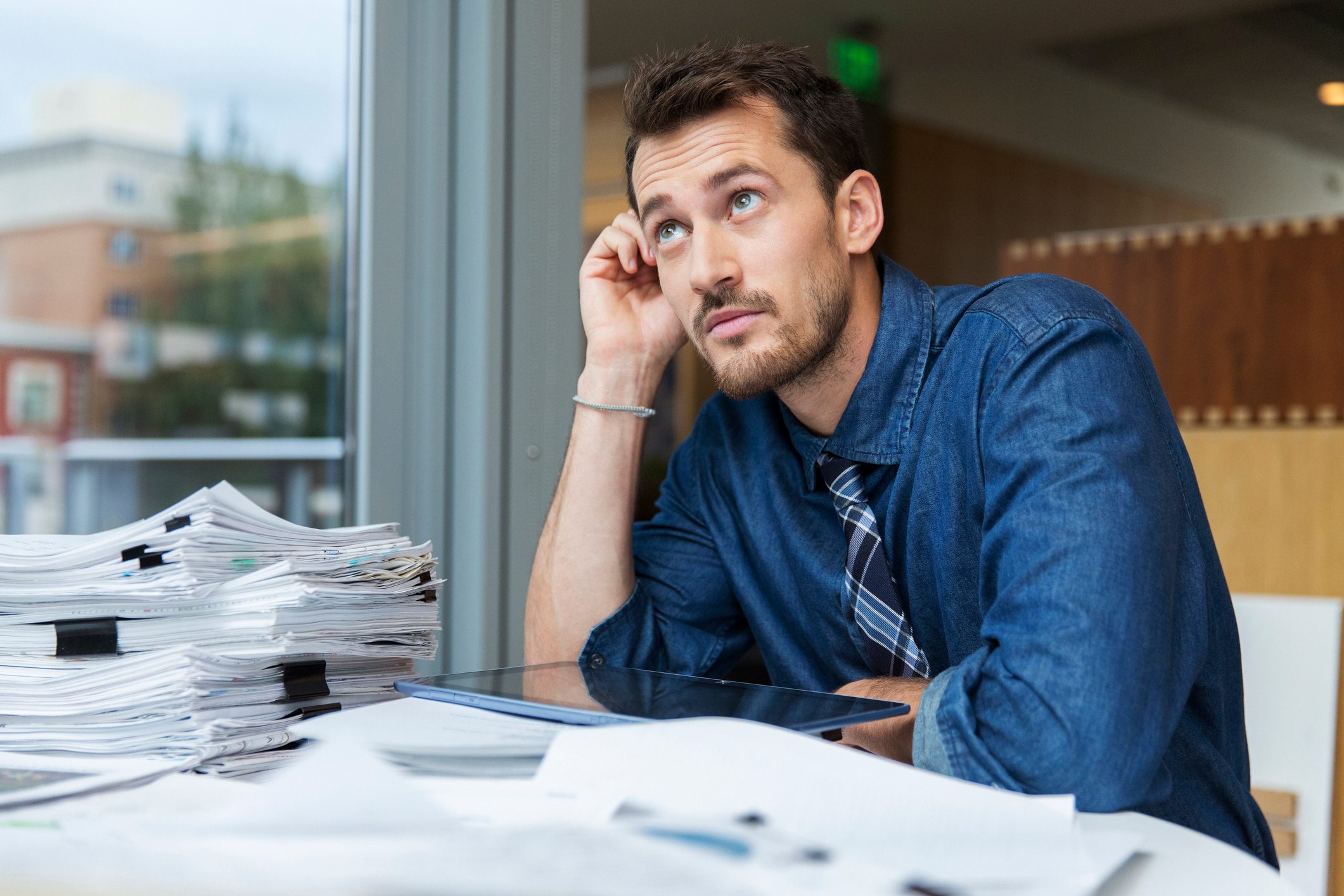 Male professional at work desk looking out window