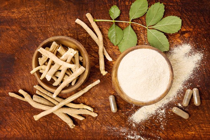 Ashwagandha root, powder, and capsules on wood table