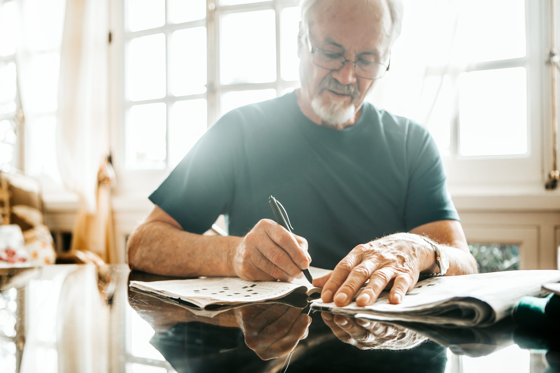 cropped image of senior men writing crossword on newspaper