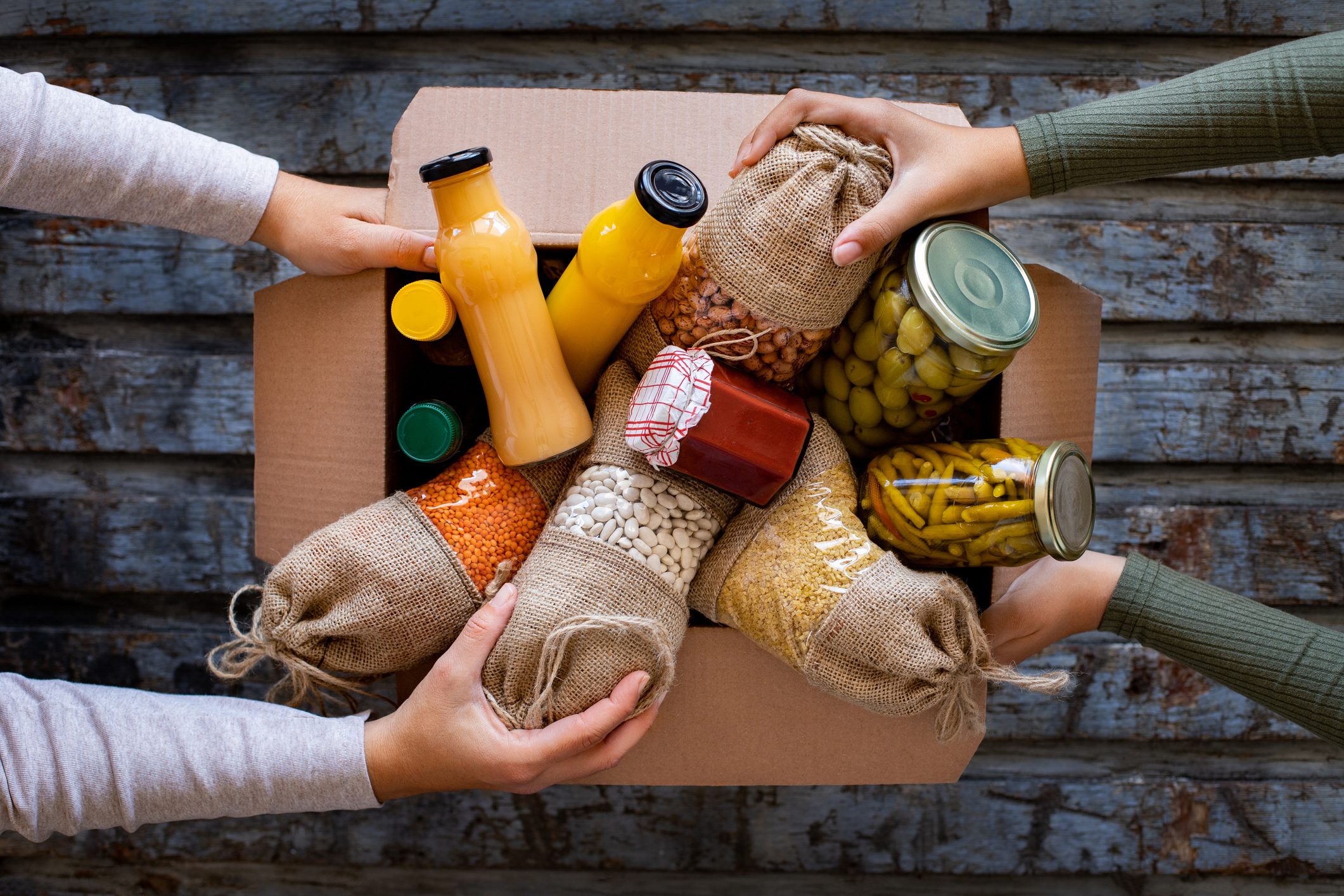 two people preparing a box of food for donation
