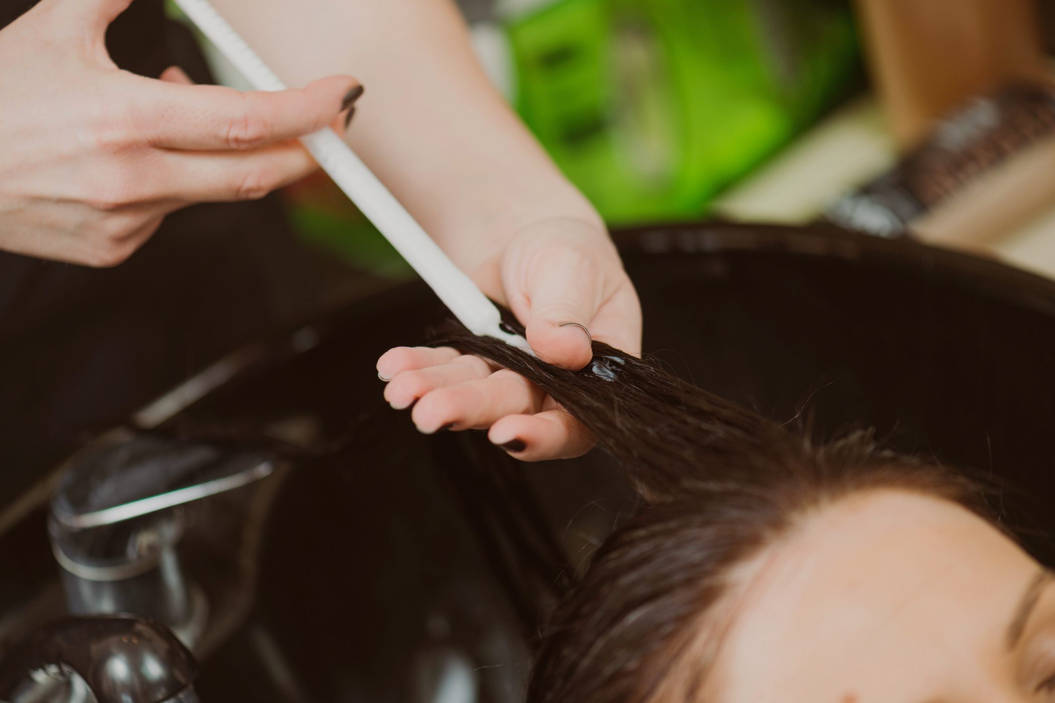 close up of hair stylist applying hair botox to client's hair