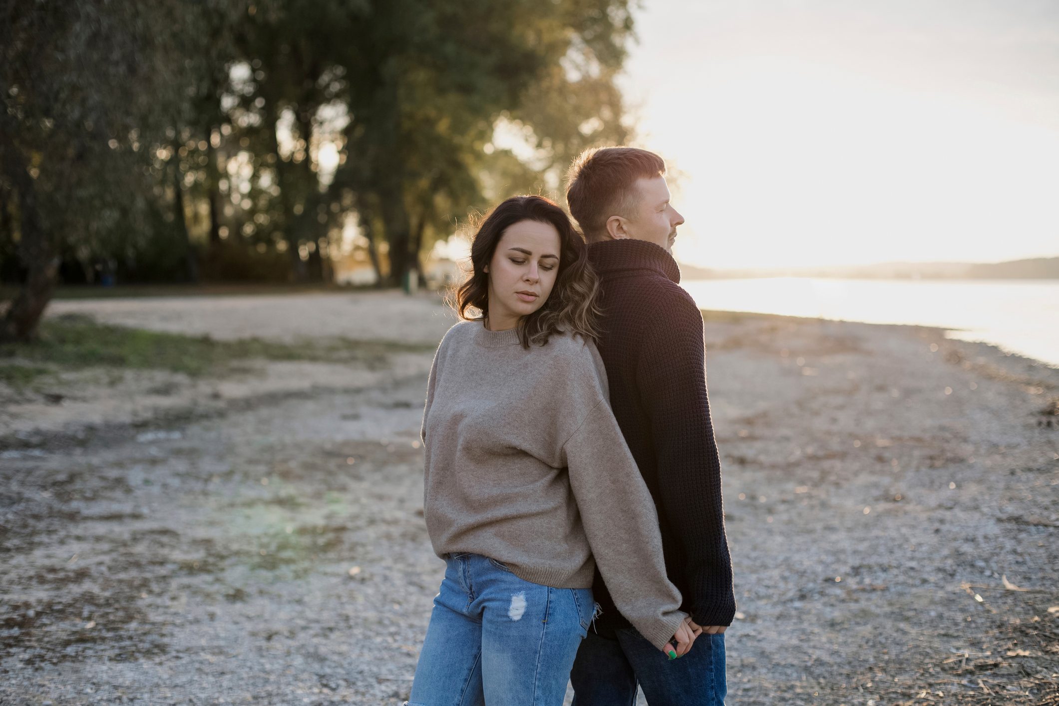 Man and woman standing back to back on the beach