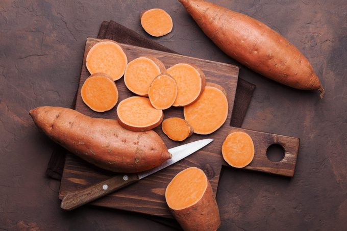 Sweet potato on wooden kitchen board from above.