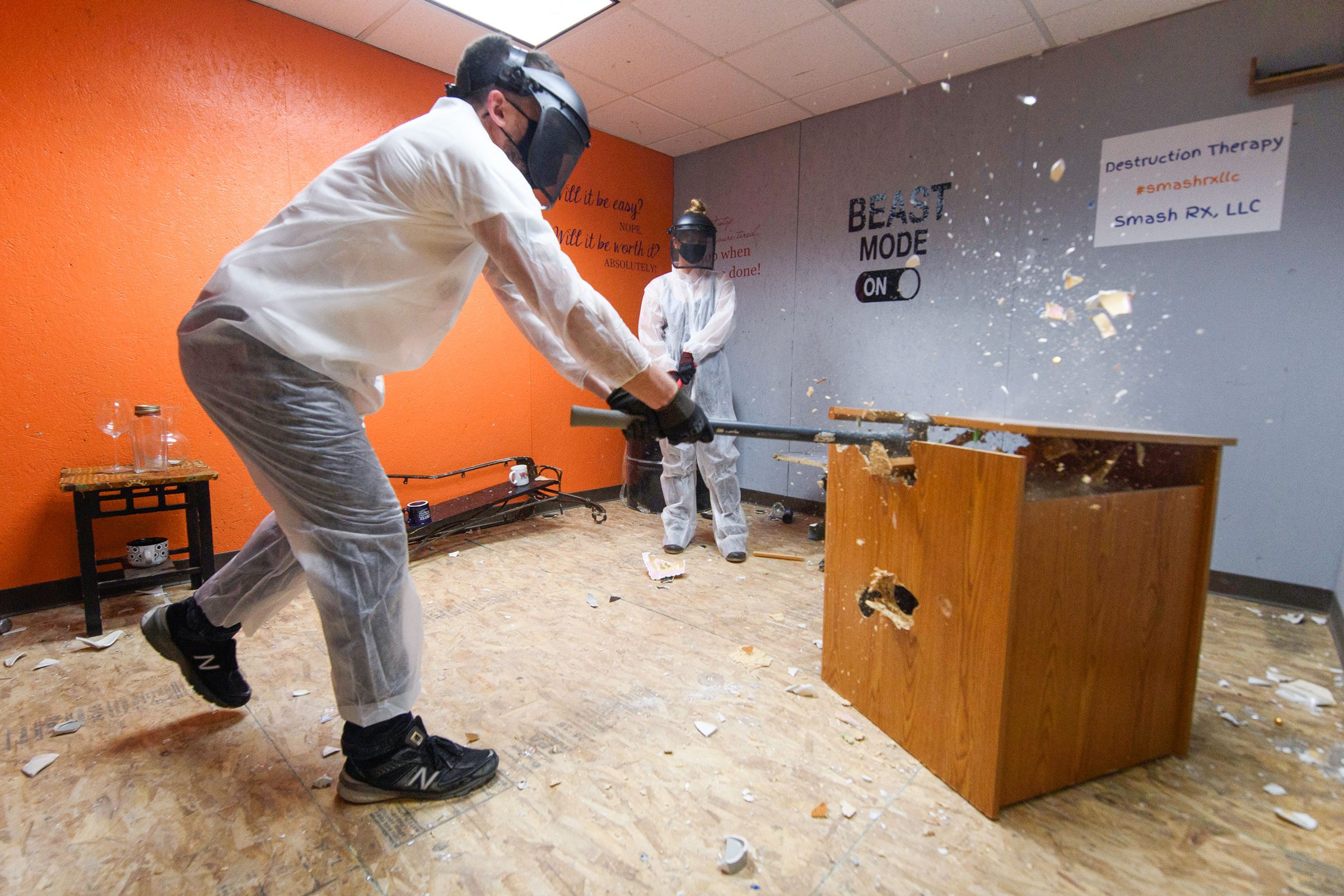 a person used a sledgehammer on a wooden piece of furniture during a therapy session in a rage room