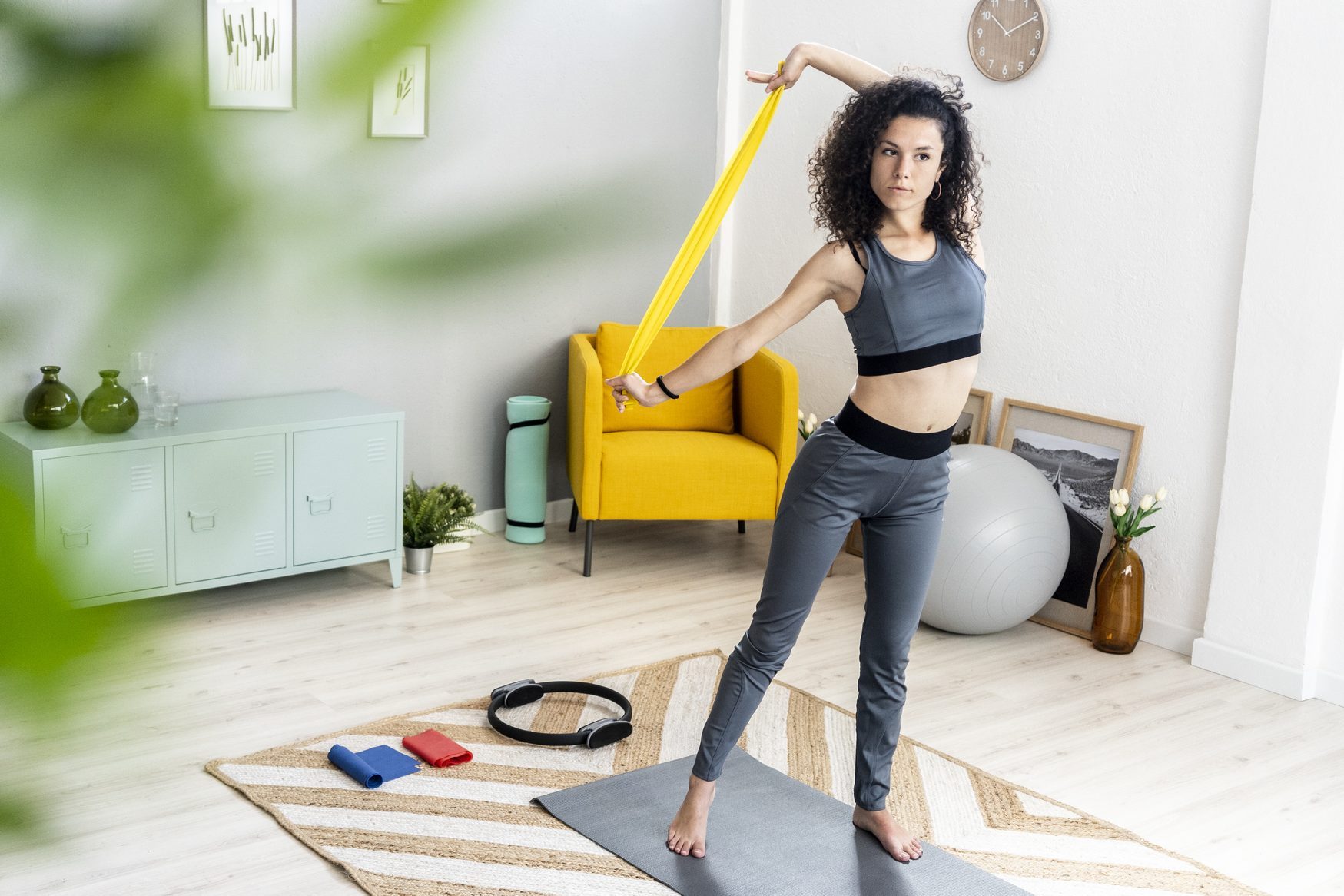 Young woman looking away while exercising with resistance band at home