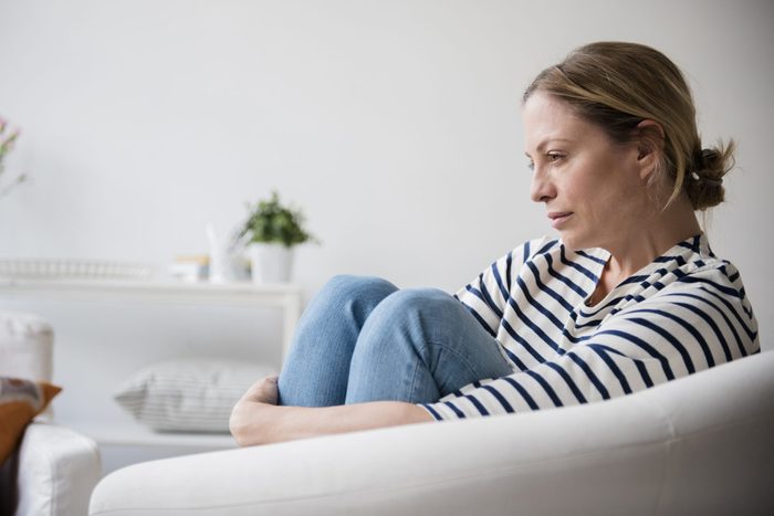 Caucasian woman sitting in armchair holding legs