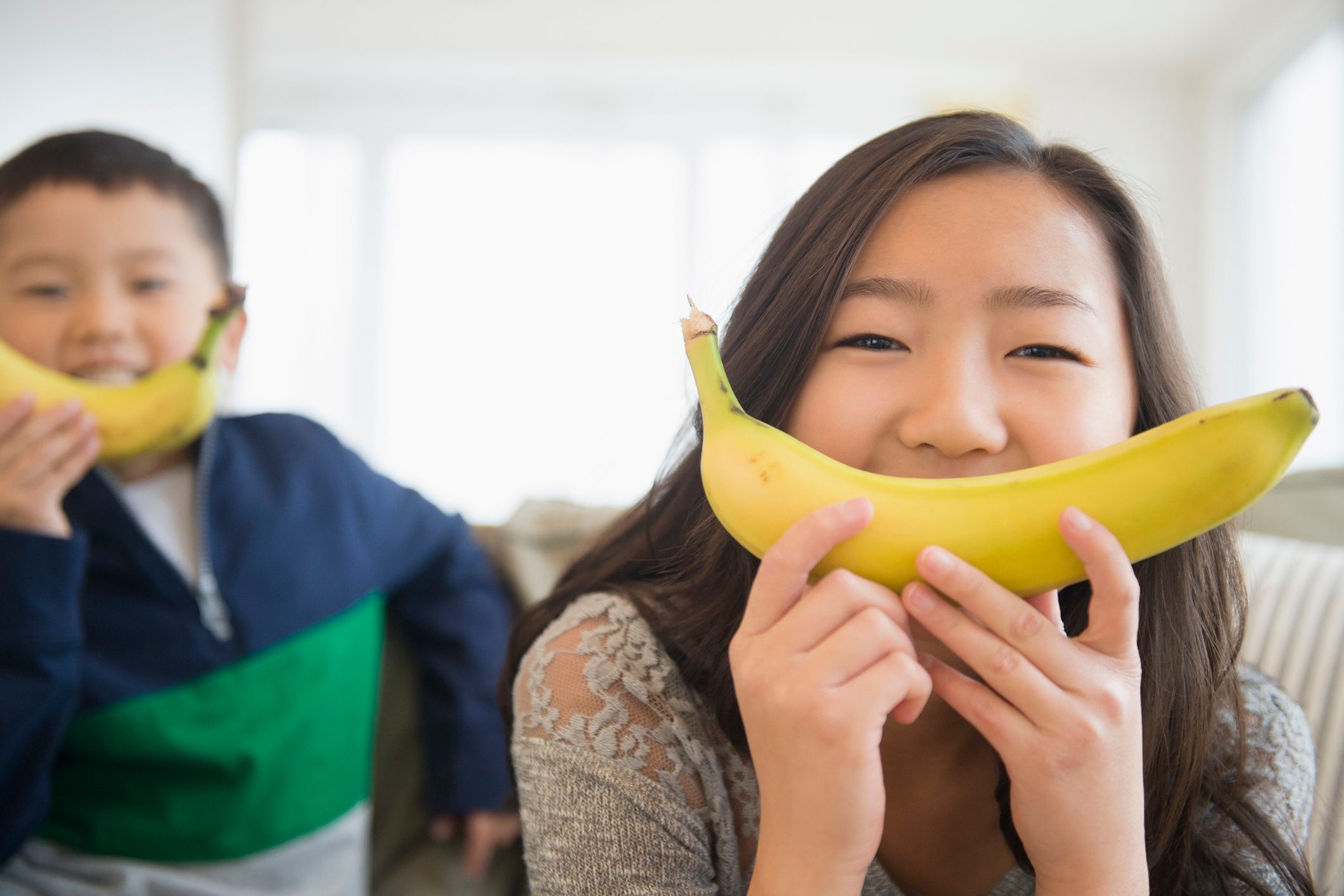 children holding bananas in front of faces for smiles