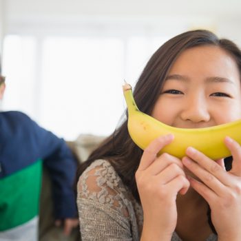 children holding bananas in front of faces for smiles