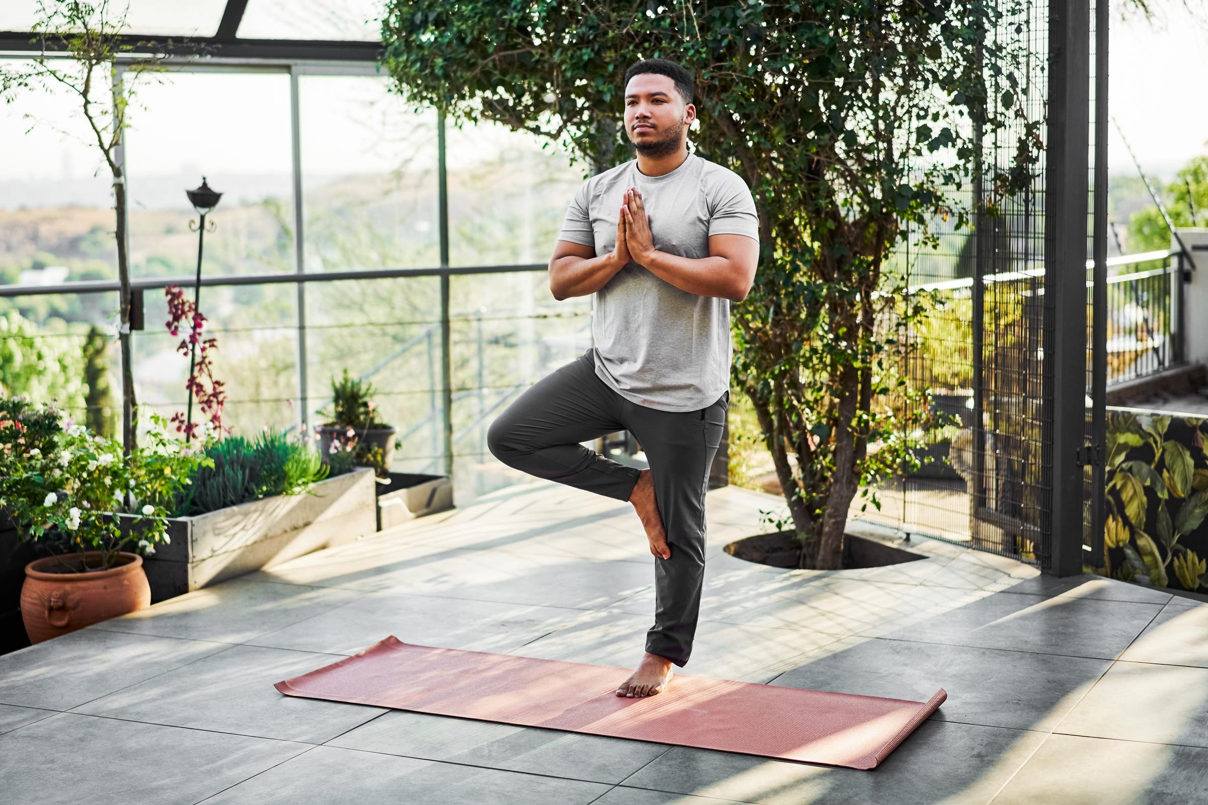 man outside does bone strengthening yoga pose, the tree