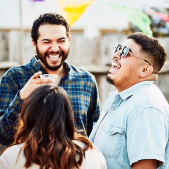 Laughing friends hanging out during backyard barbecue on summer evening