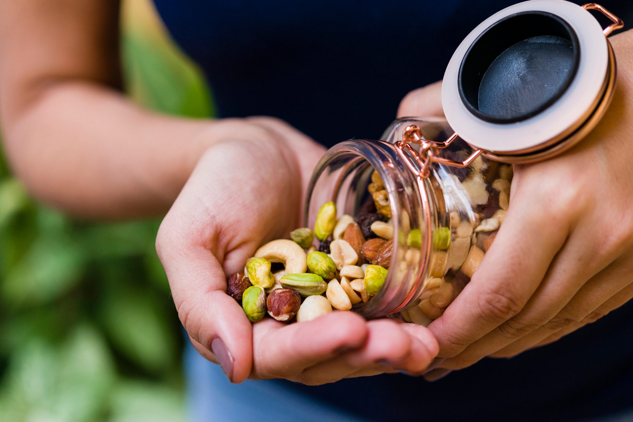 anonymous person pouring nuts into one hand from a glass jar