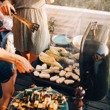 Midsection of female friends grilling food on barbecue grill at yard