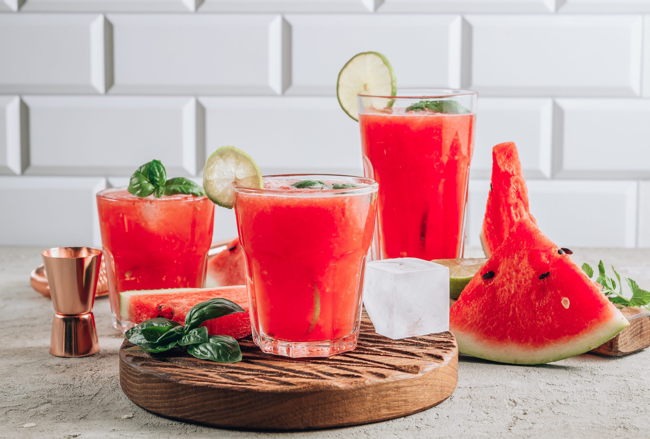 Watermelon lemonade with lime and fresh basil leaves on concrete background. Refreshing summer drink