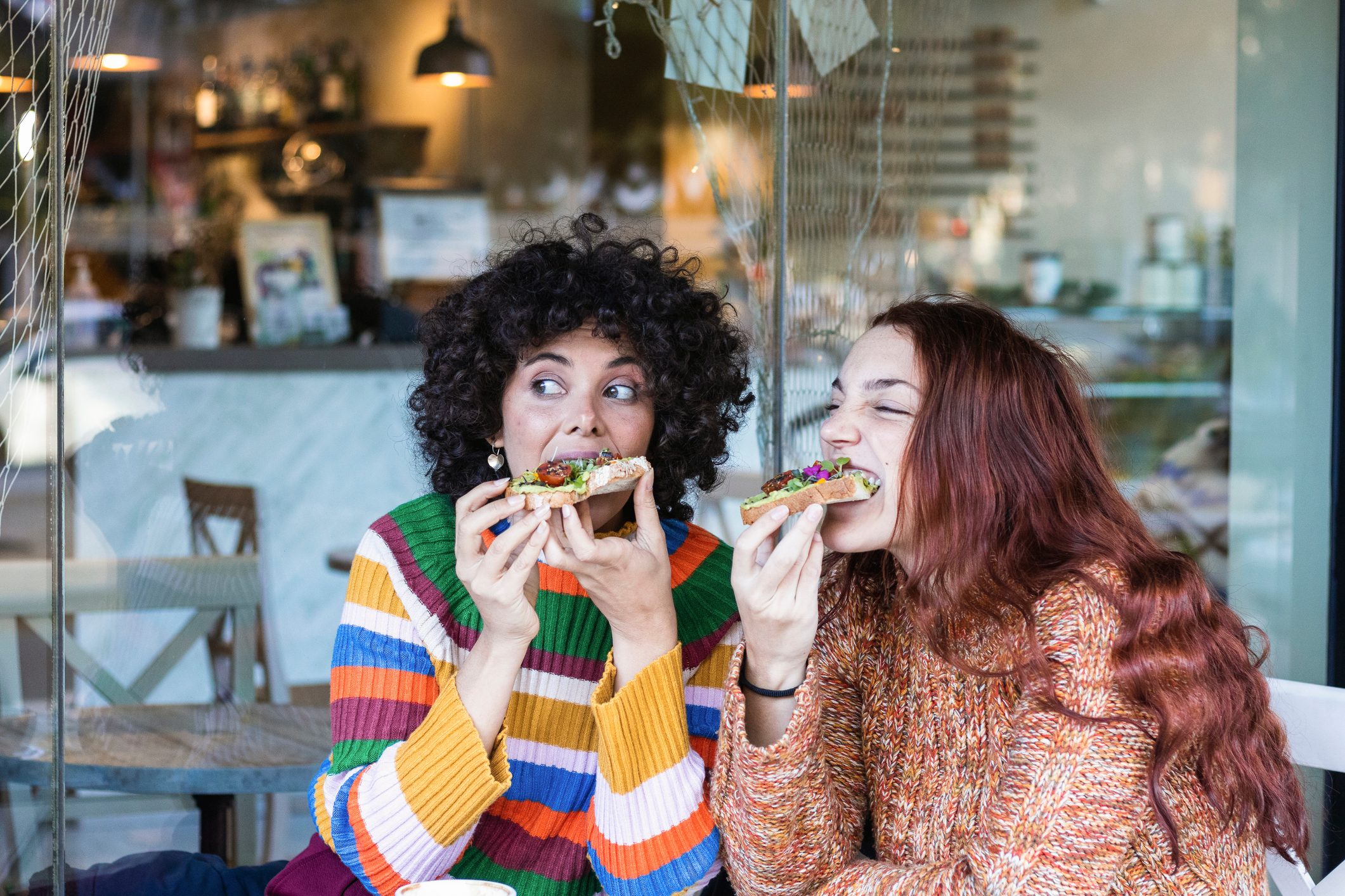 Young woman having breakfast with friend while sitting at restaurant