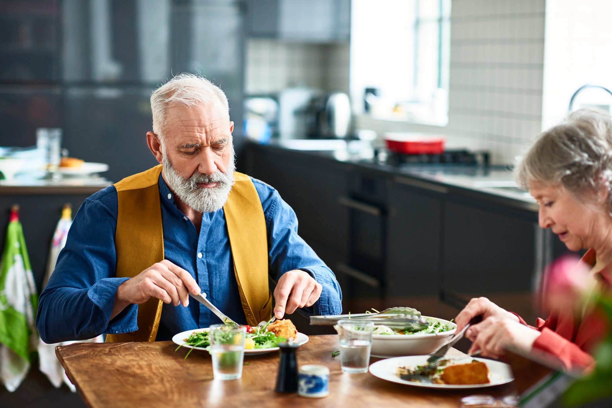 Couple eating healthy salad for lunch sitting at a table