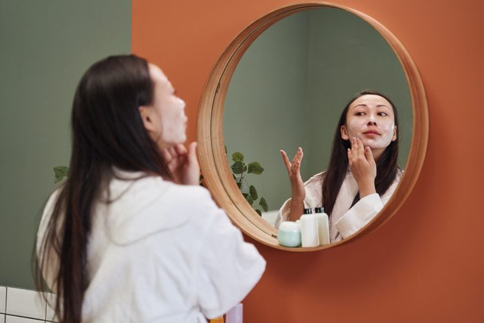 Asian woman applying moisture cream at her face