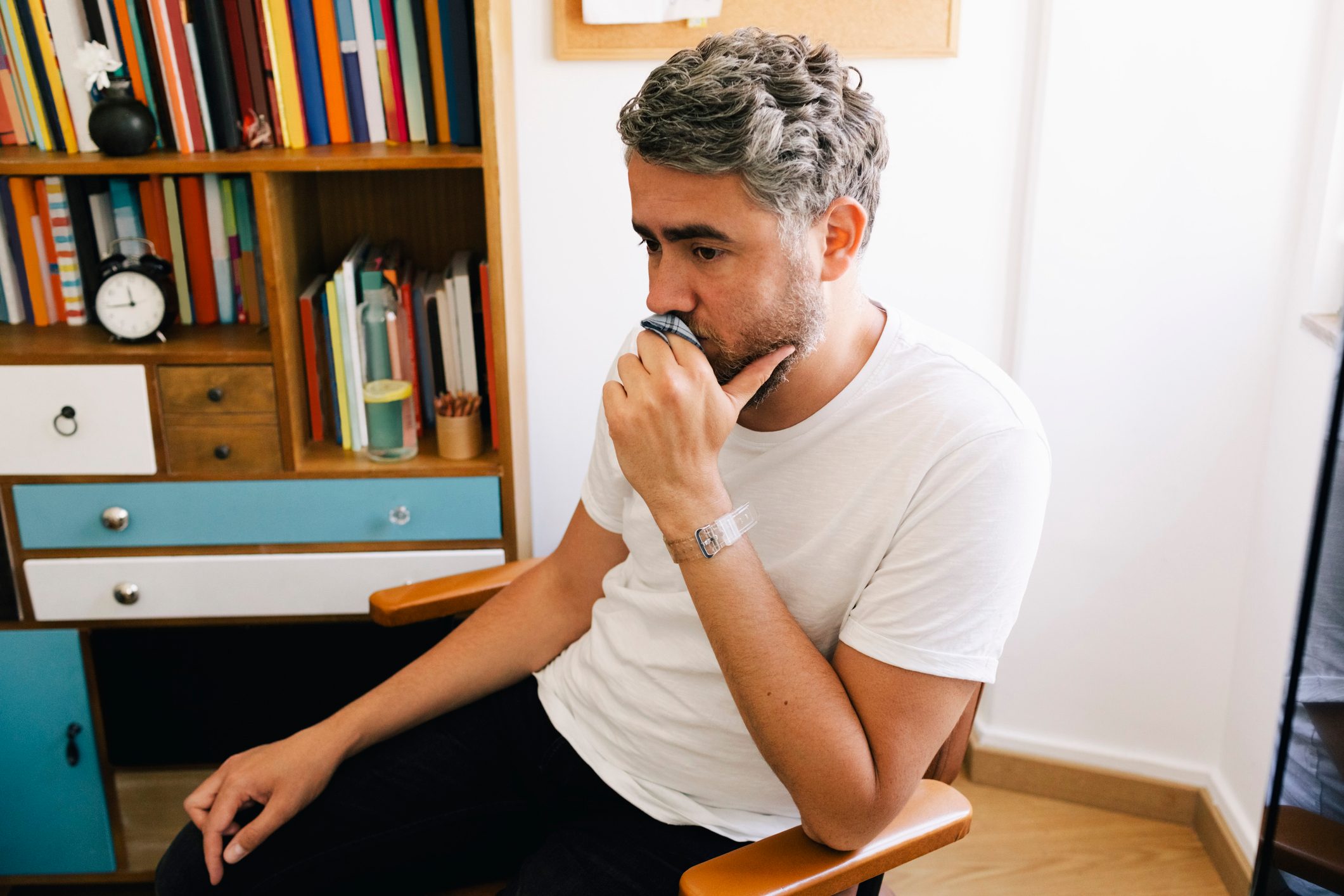 Contemplative depressed man sitting on chair in therapy office