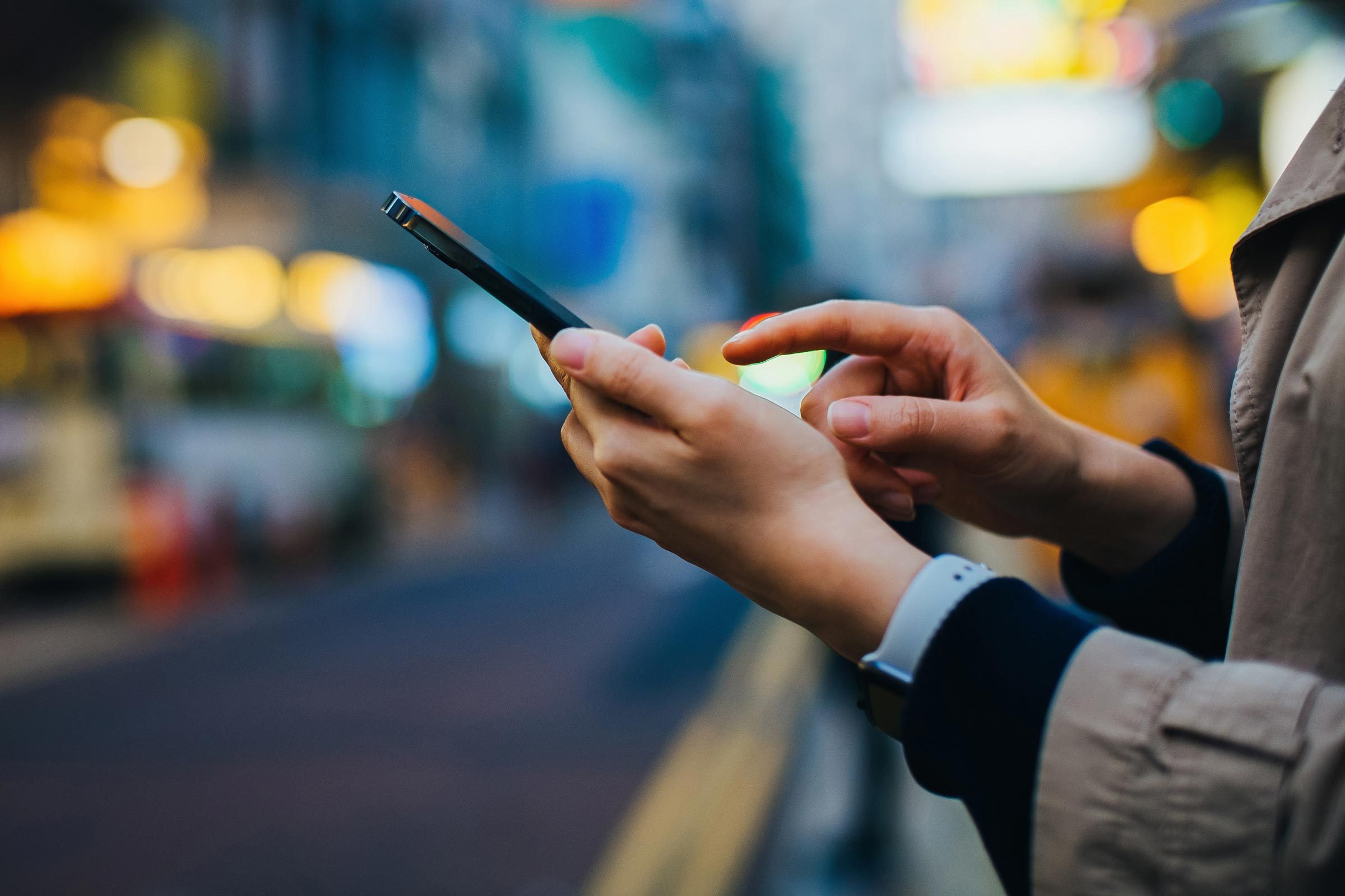 close up on hands of anonymous Woman Using Iphone with blurred city background