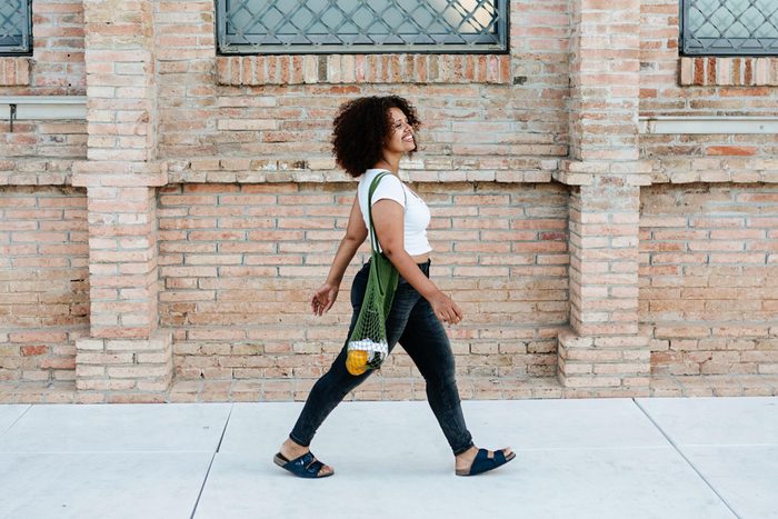 smiling Woman Walking down the sidewalk along a brick building