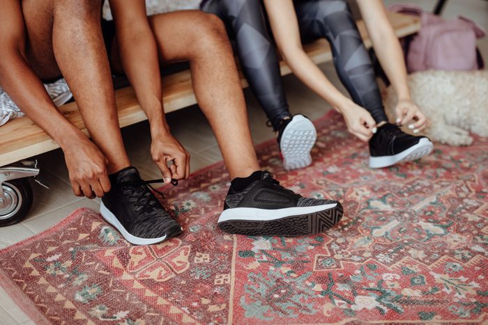 Close up of couple tying shoes before morning run
