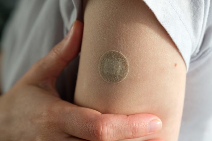 A girl or woman holds her hand, which is covered with a plaster or adhesive bandage after vaccination or injection of medication. The concept of medicine and healthcare, prevention and treatment of diseases. First aid. Repeated vaccination, revaccination.