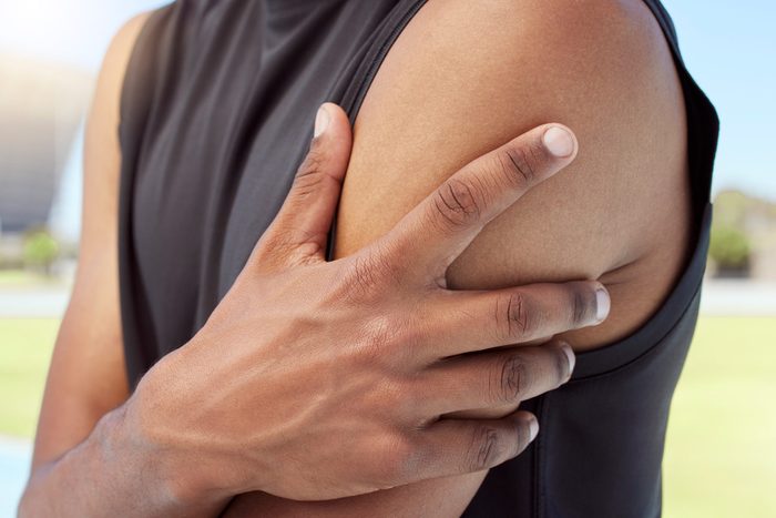 Closeup of african american sportsman suffering from shoulder pain while training. Zoomed in on unknown black man holding and rubbing sore arm with. Overworking muscles causing tension