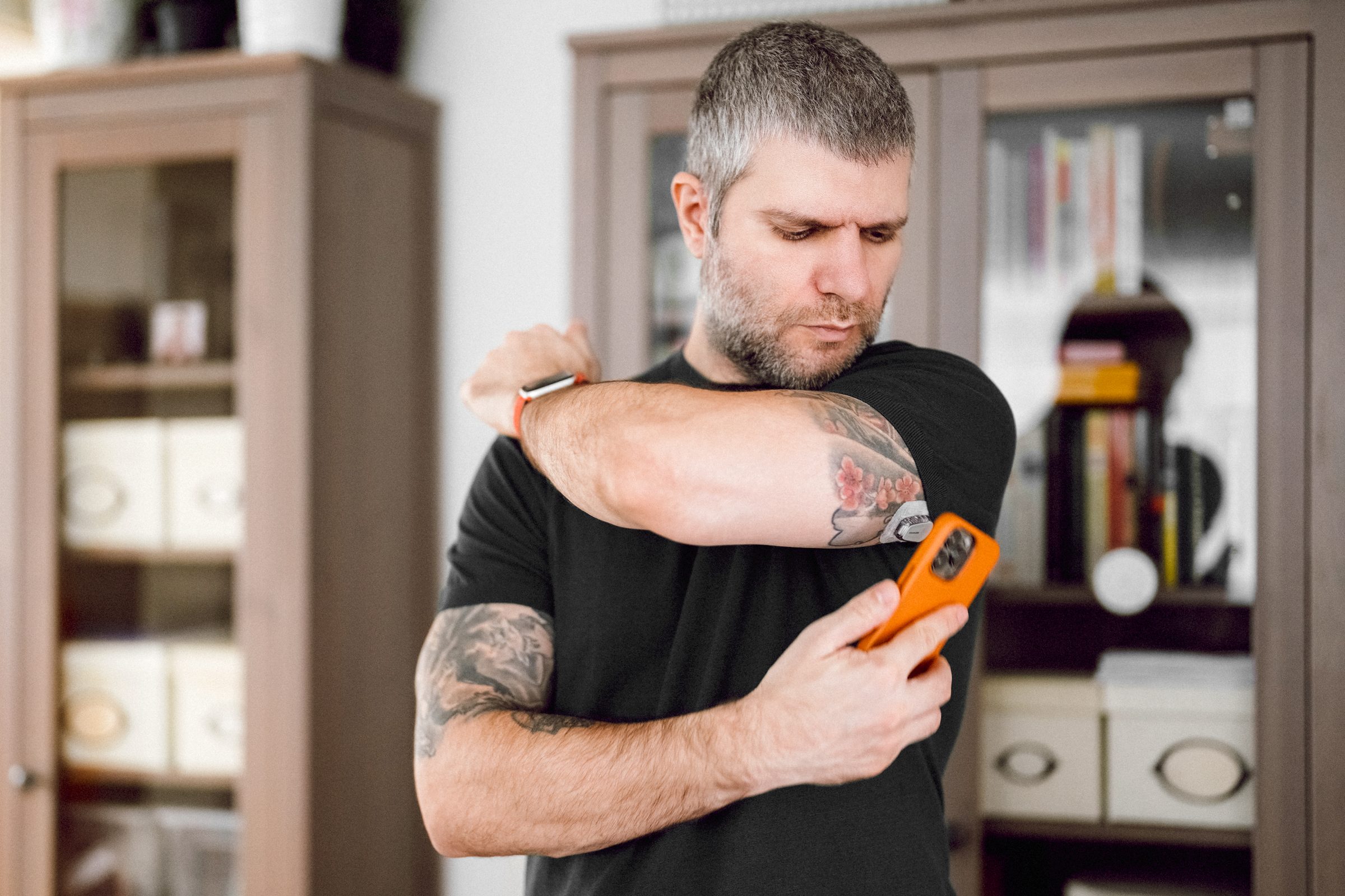 Man is wearing small sensor on the back of upper arm for measuring glucose levels due to diabetes