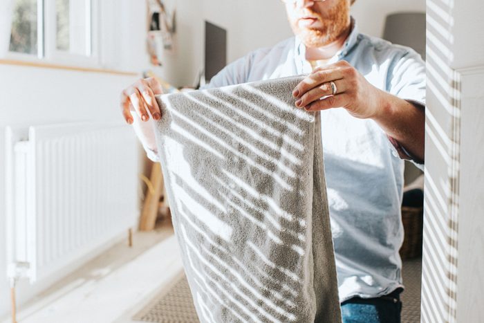 Man folding laundry in a sunny room.