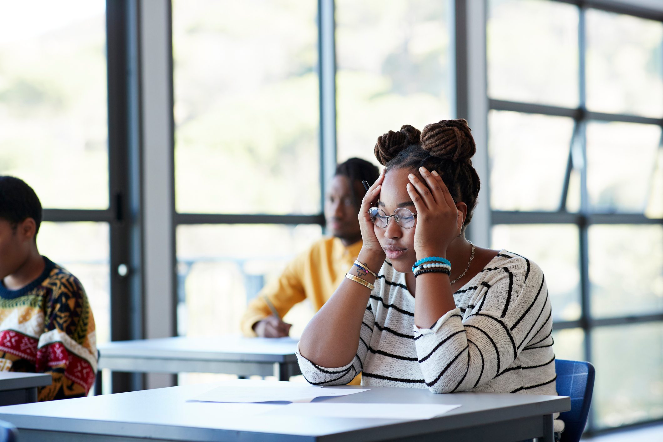 Worried student sitting with head in hands at desk experiencing brain fog