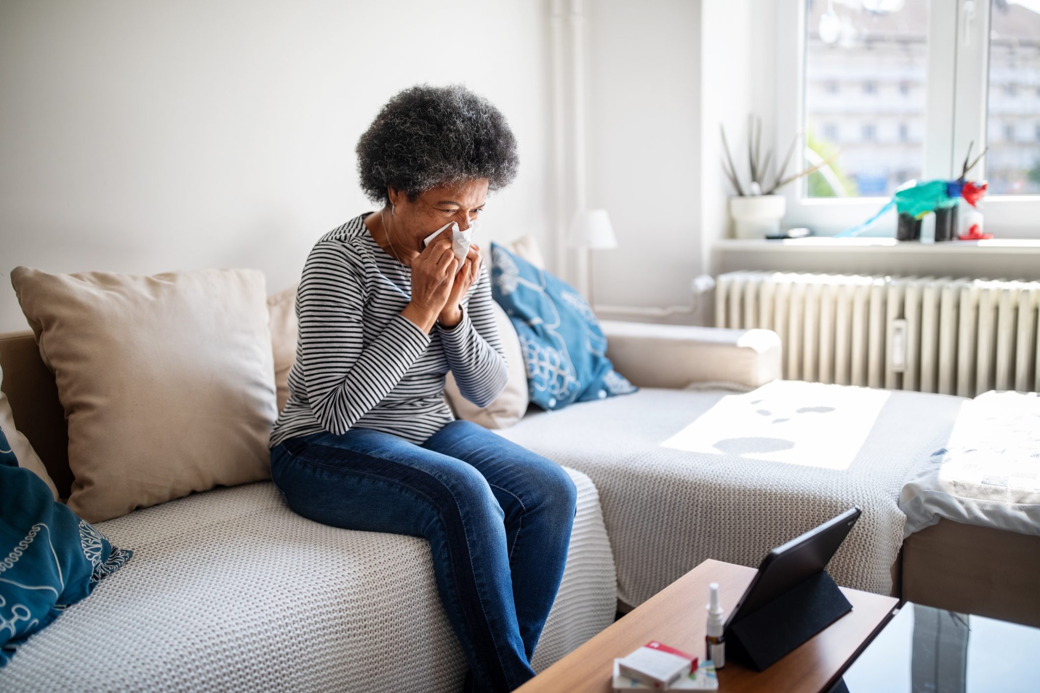 Sick woman blowing her nose on the couch