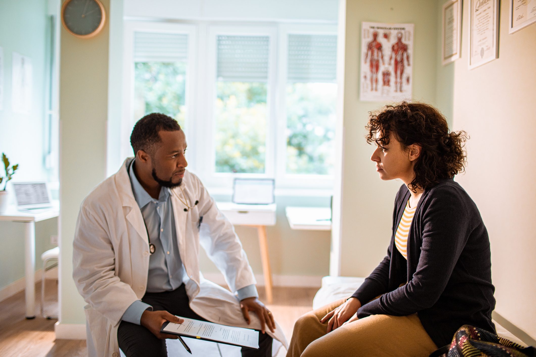 doctor with a clip board and a patient talking in a doctors office