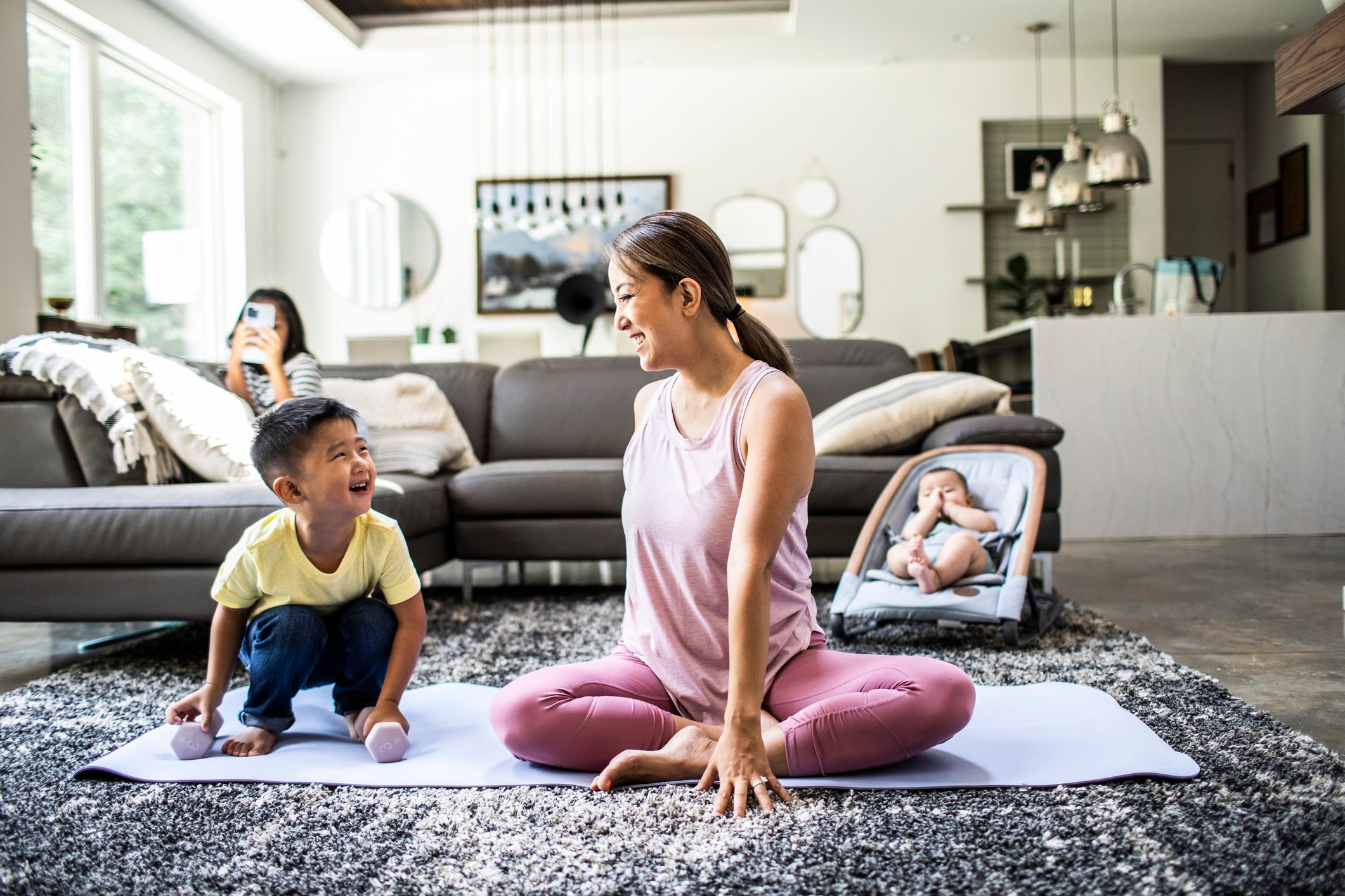 Mother doing yoga at home surrounded by children