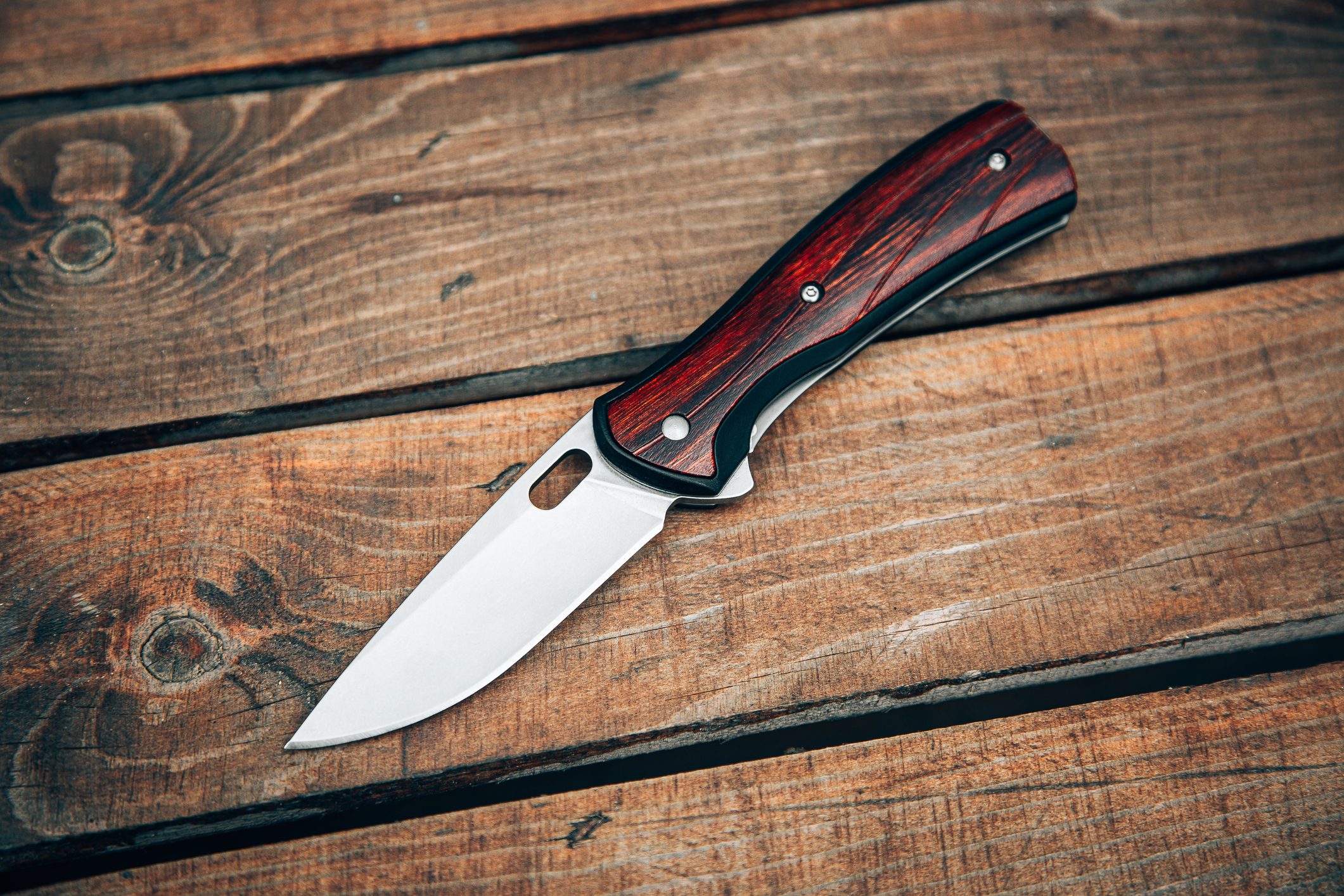 Folding pocket knife with wooden handle. A small knife on a wooden surface.