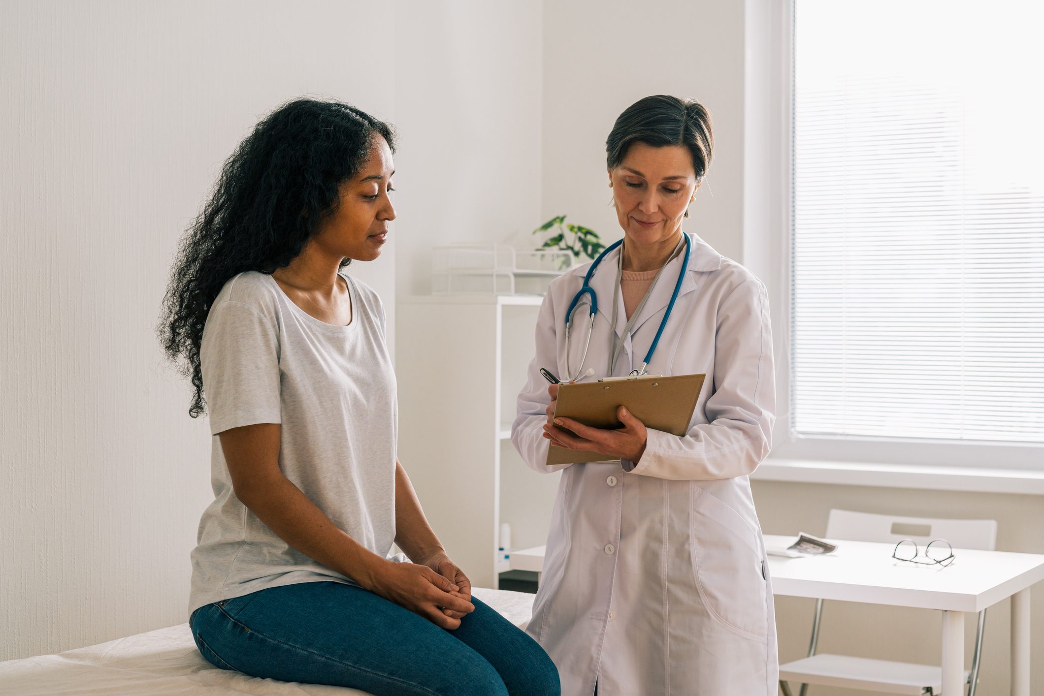 African-American female patient visiting doctor office telling about symptoms. Medical consultation