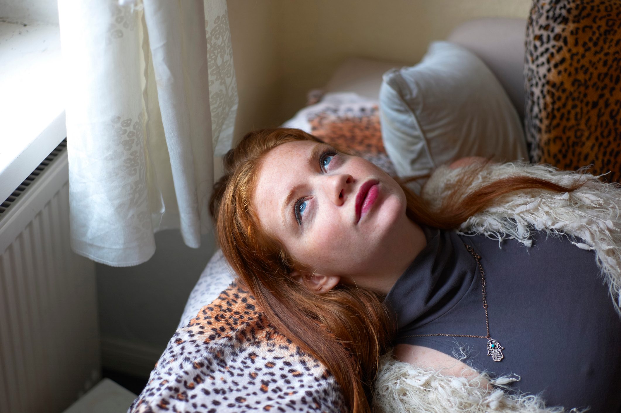 Woman lying on her couch gazing out of the window and thinking about her future