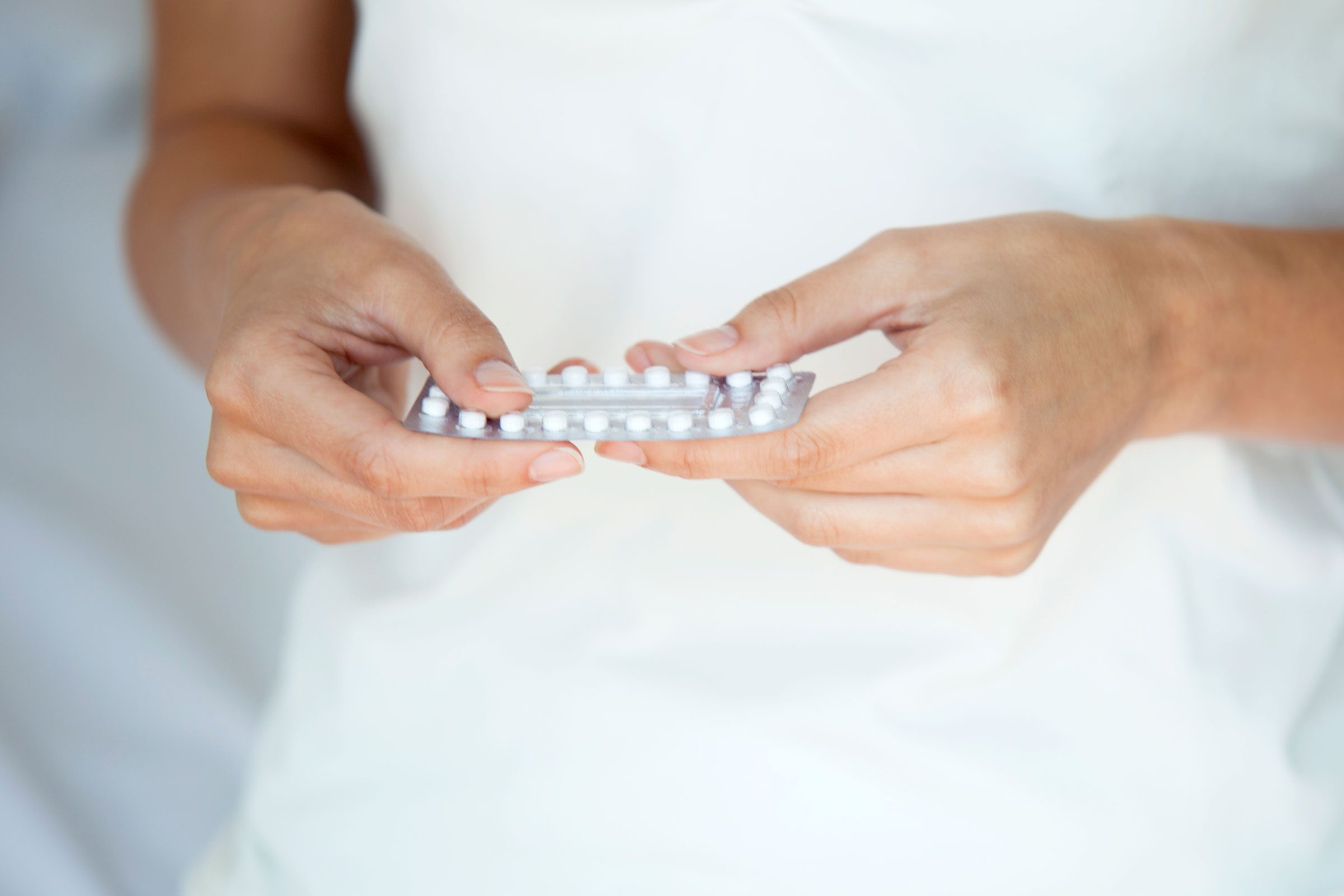 a woman holding birth control pills