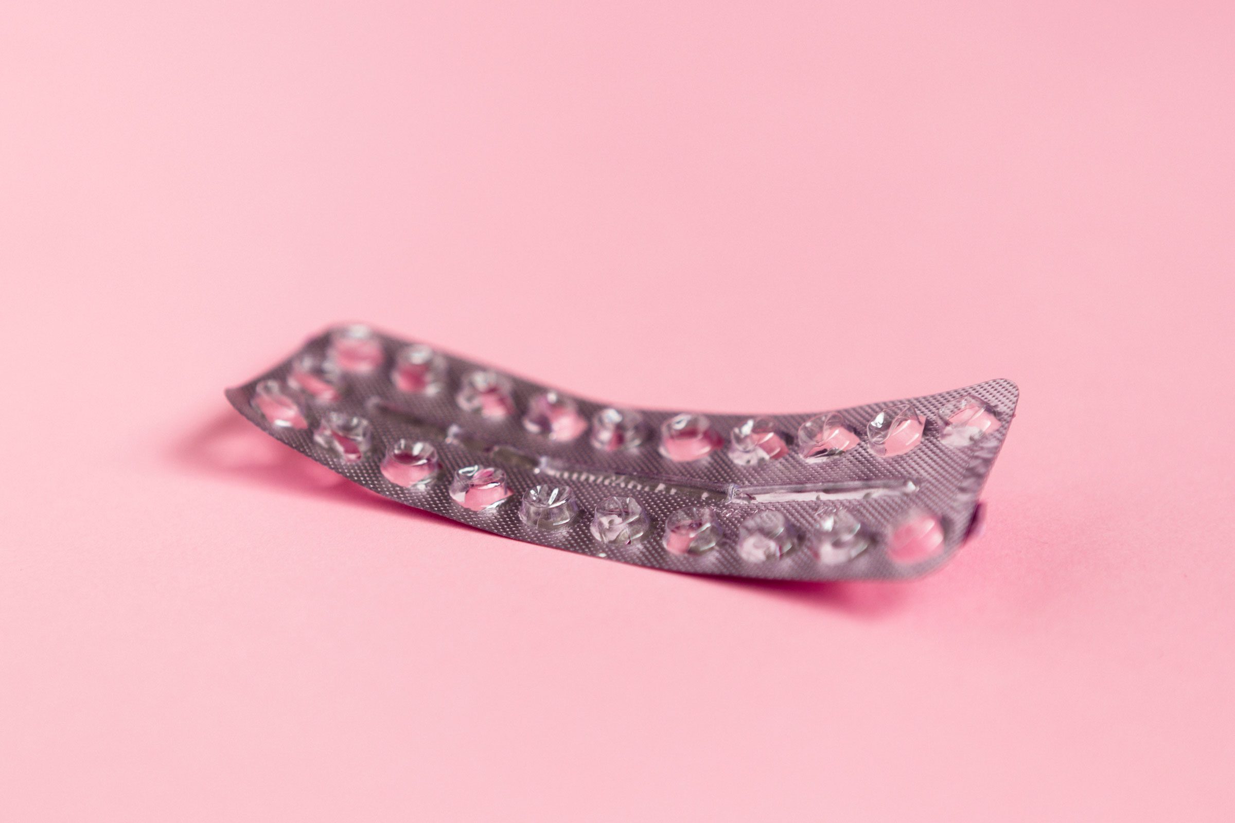 empty birth control package on a pink background