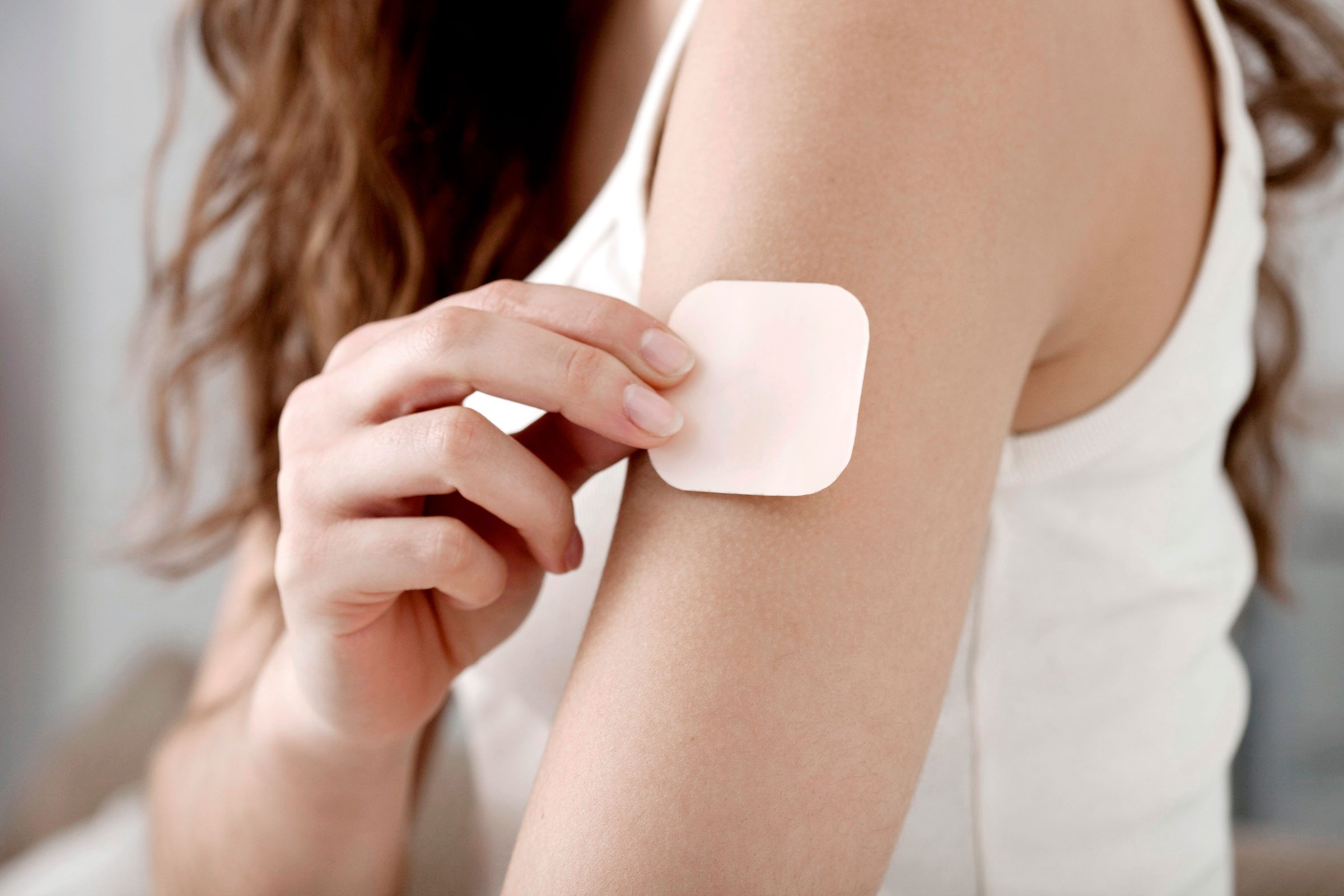 woman putting a birth control patch on her arm