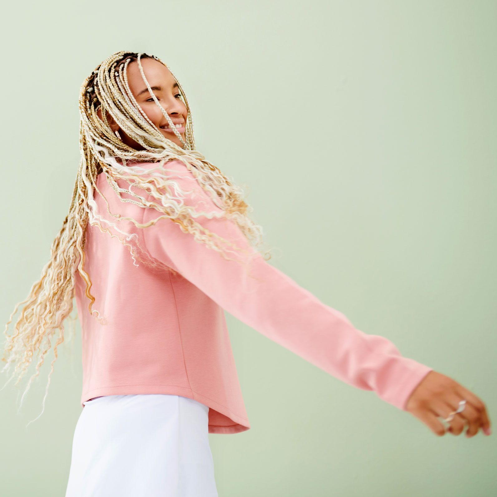 woman twisting and spinning and exercise with a happy look on her face on a green background