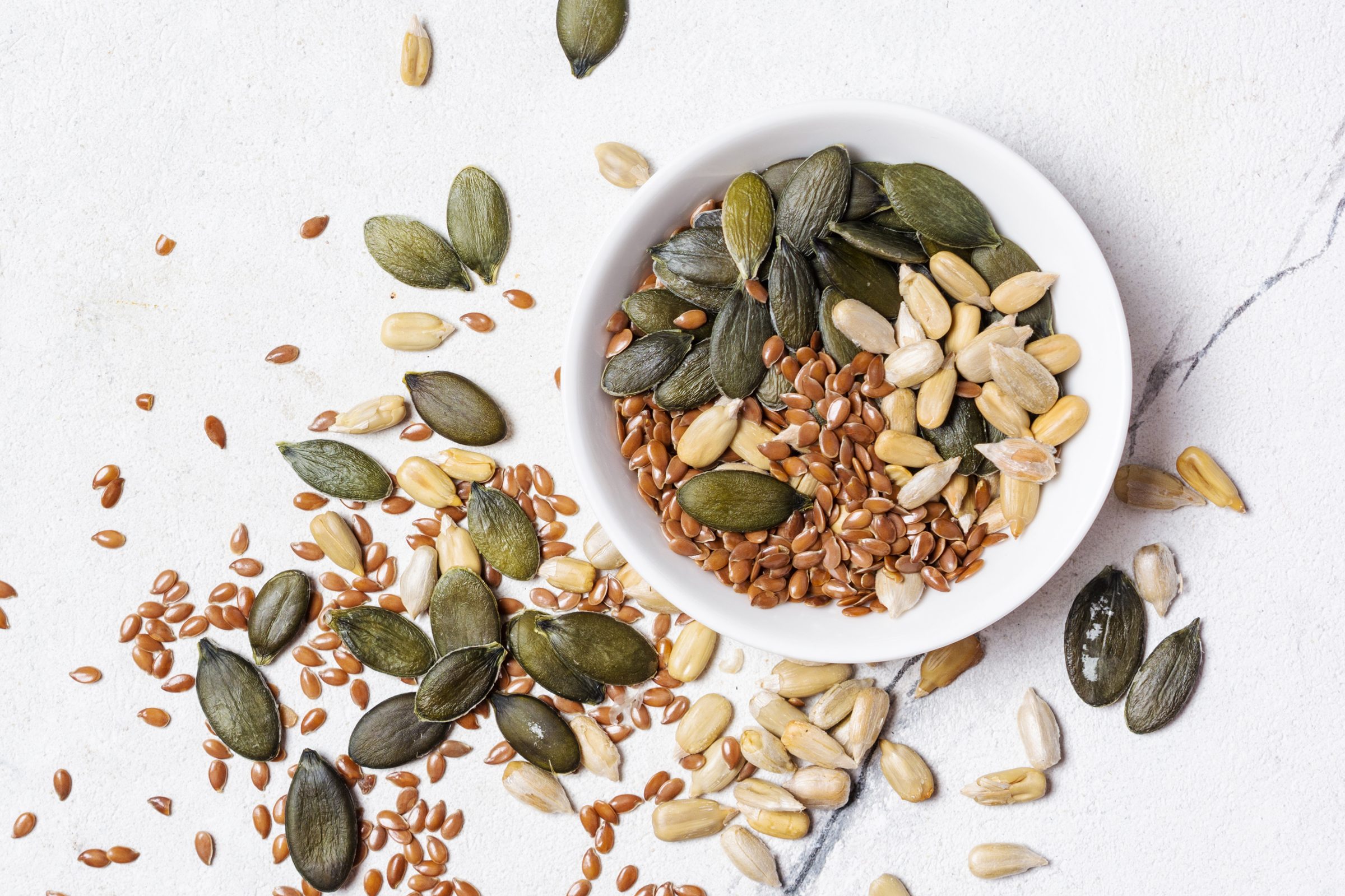bowl of mixed seeds with some spilled on the counter