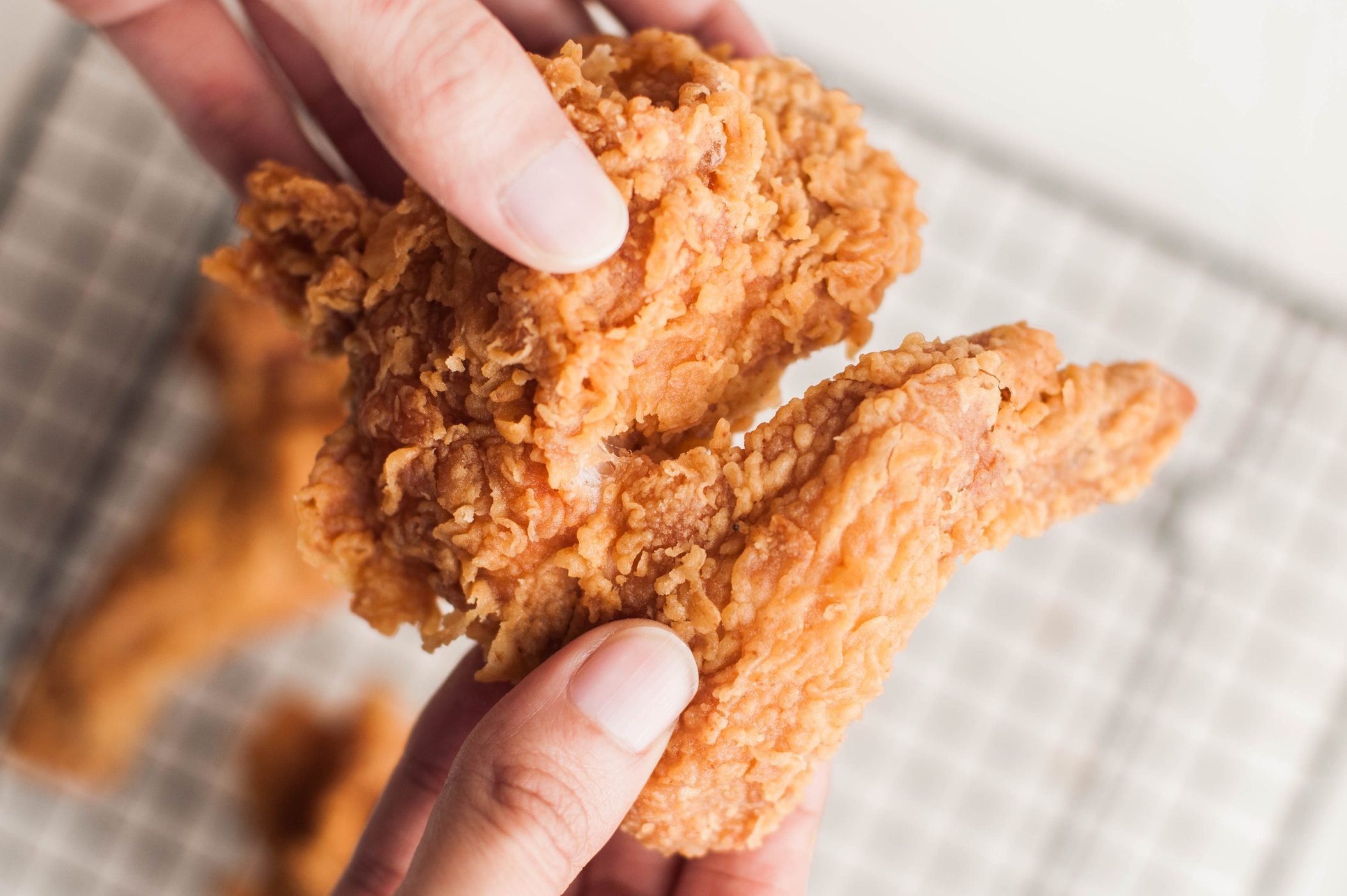 High angle view of Southeast Asian person holding fried chicken wings