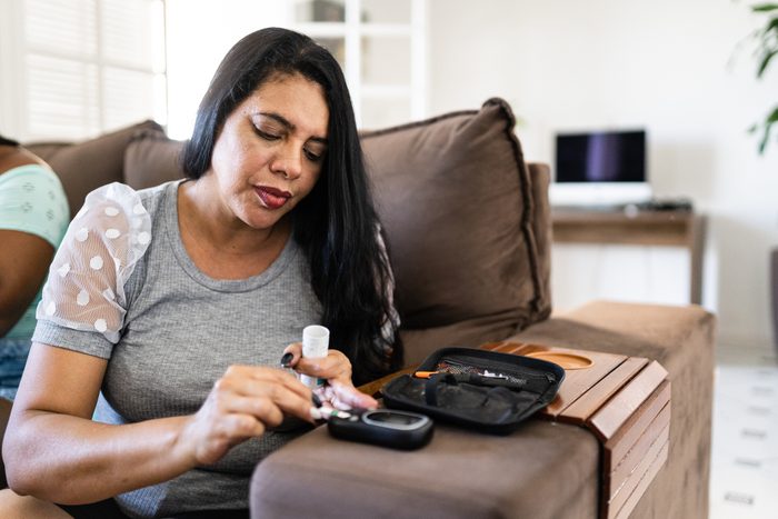 Woman checking blood sugar level at home