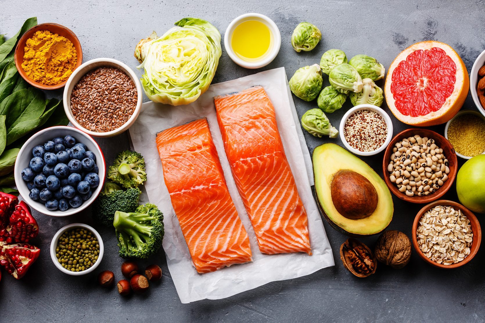 fish, fruit, vegetable, seeds, superfood, cereals, leaf vegetable on gray concrete background