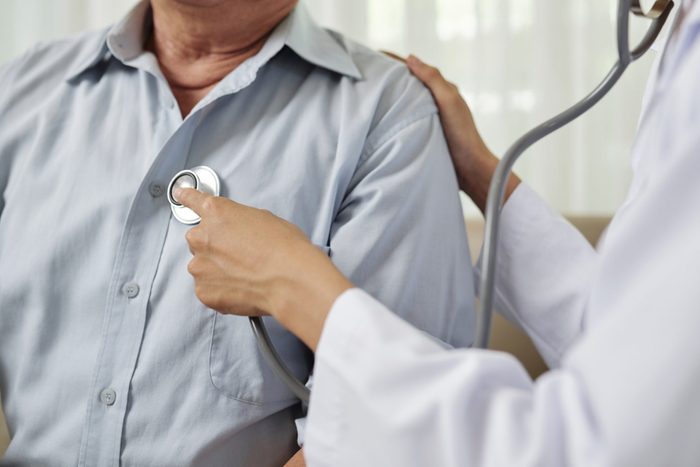 Doctor listening to senior breathing man