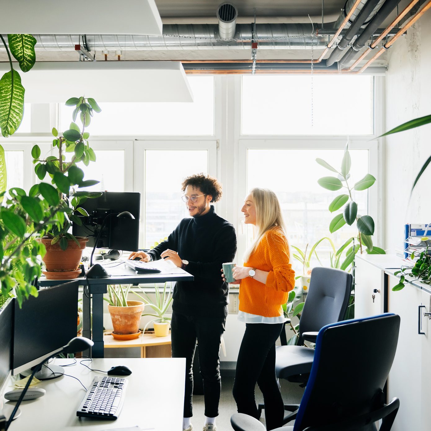 Two Colleagues Looking At Work Using Standing Desk