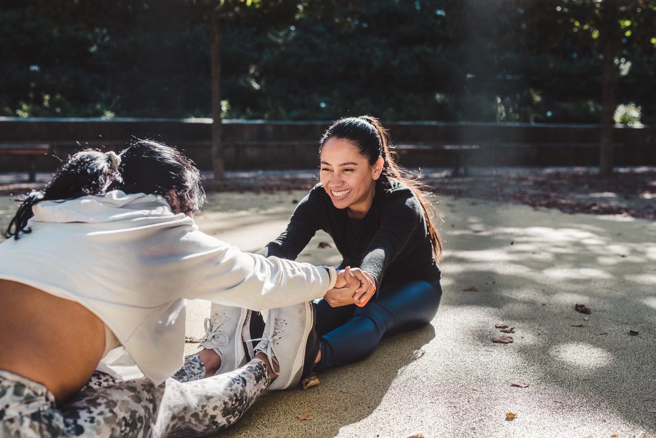 Female friends doing stretching together outdoor having fun.